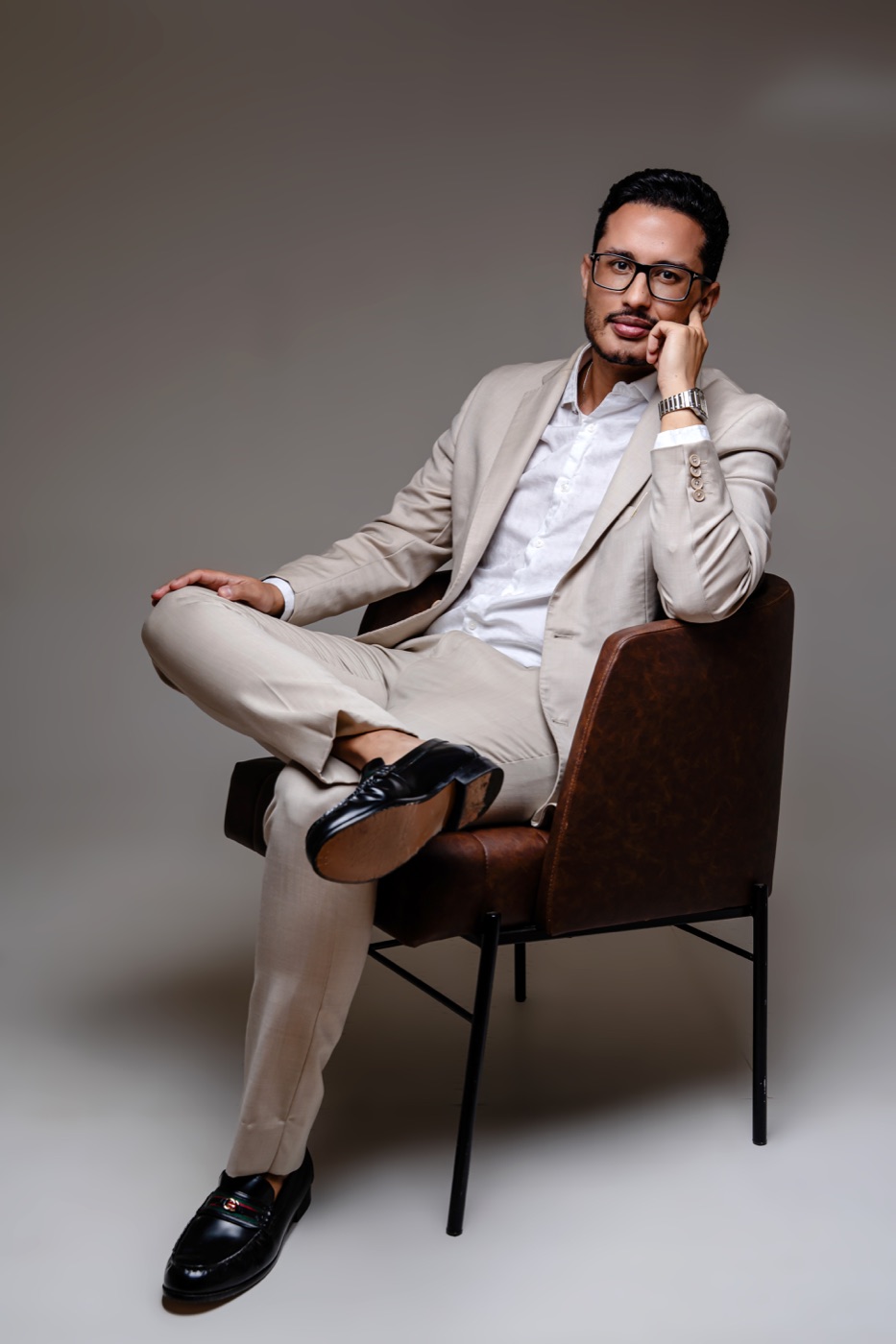 Dr. Erick Neres sentado, de terno bege, no estúdio
