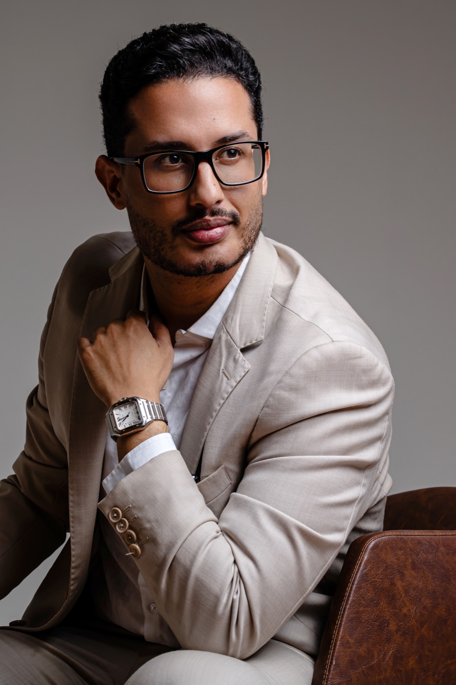Dr. Erick Neres sentado, de terno bege, no estúdio